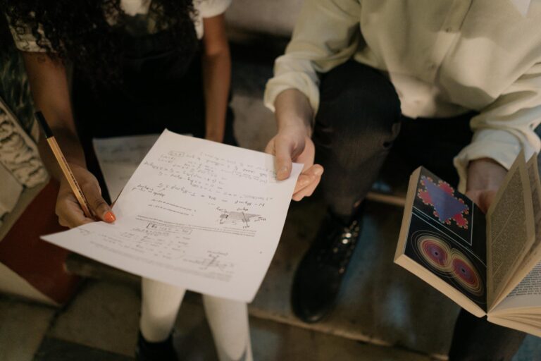 Close-up of diverse individuals studying with books and notes in an indoor setting.