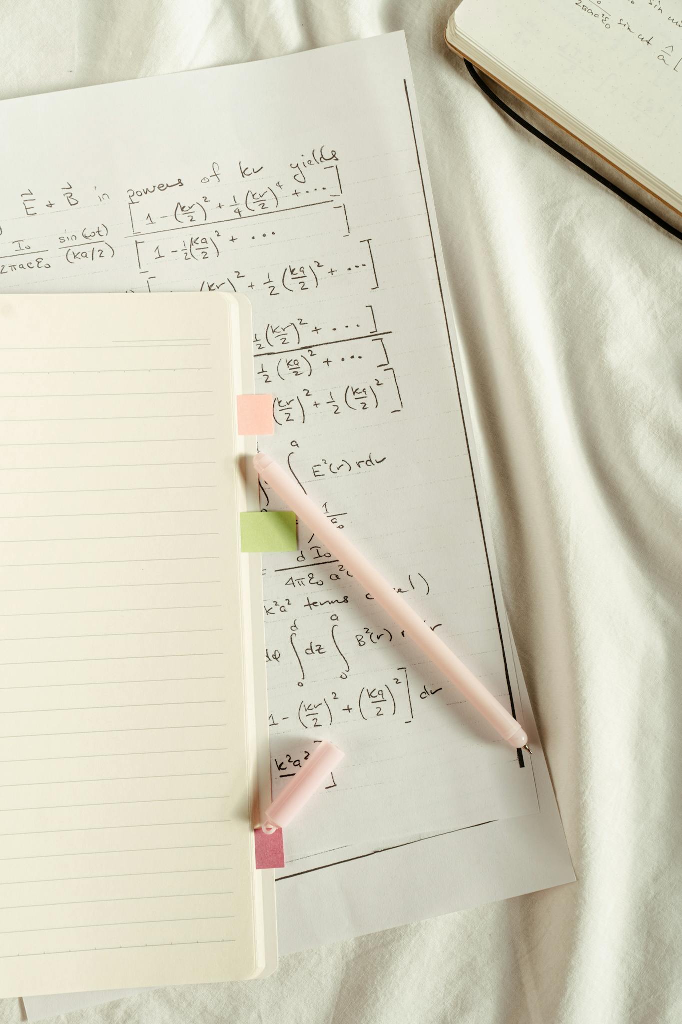 Flat lay of handwritten mathematical formulas and notes with colorful sticky notes and pen.