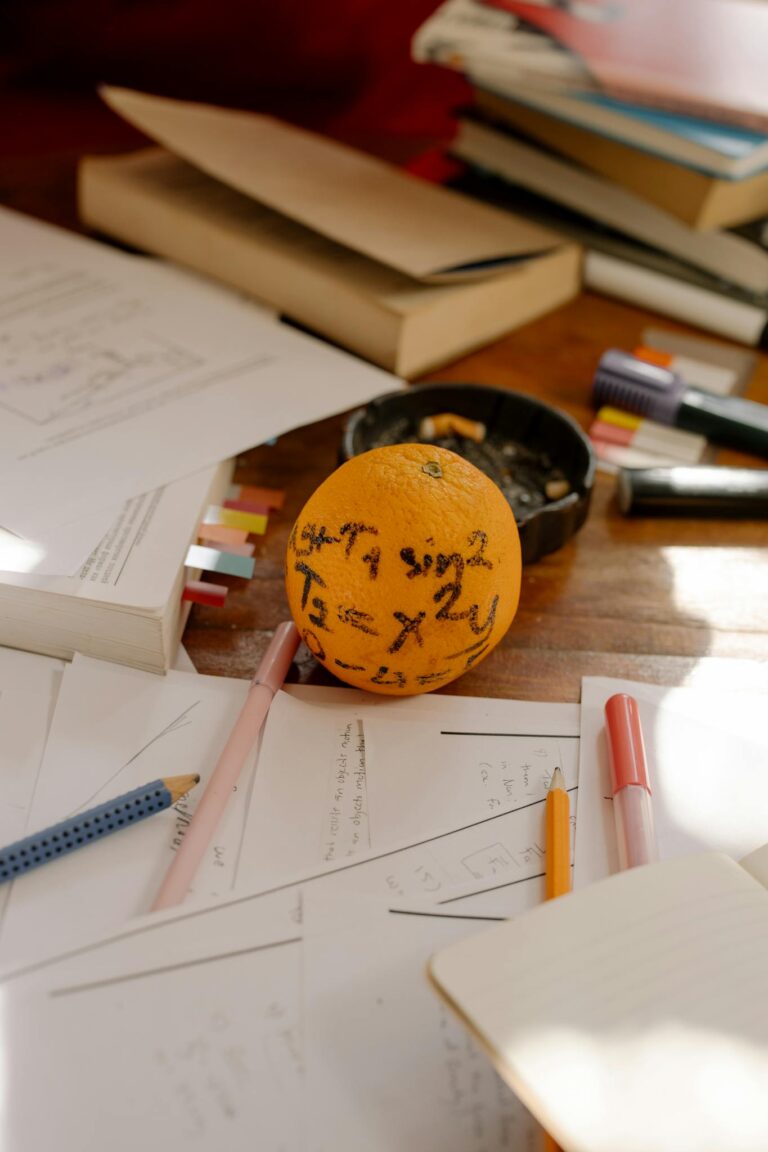 Orange with math formulas among books and study materials on wooden table.